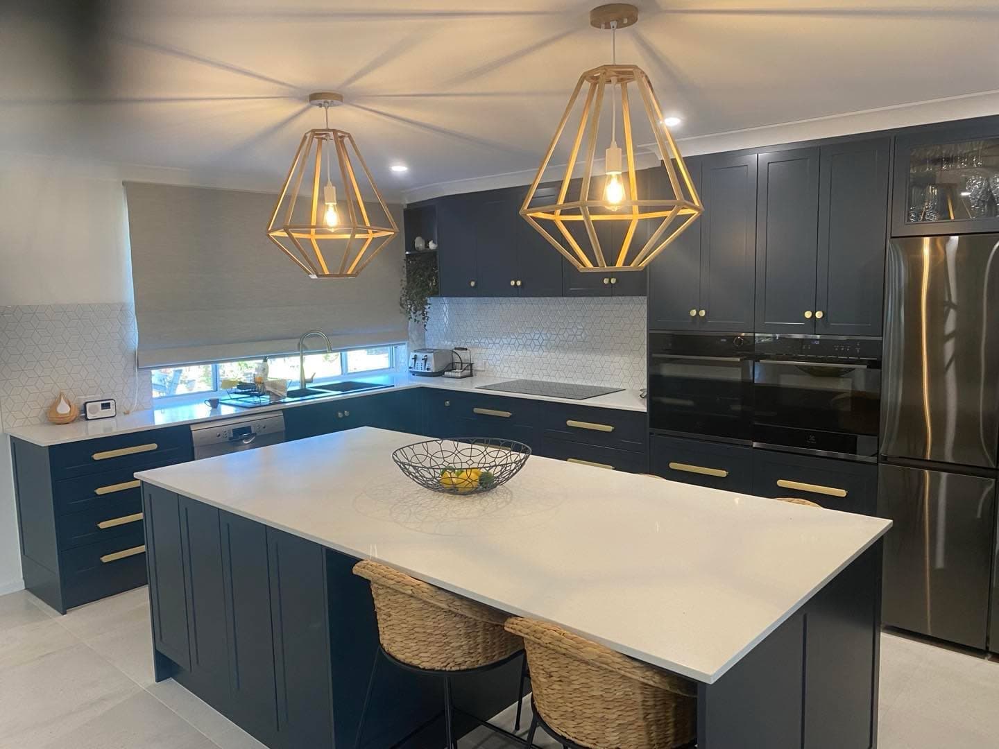 Navy shaker kitchen with brass hardware, statement timber pendant lights and a waterfall-edge island