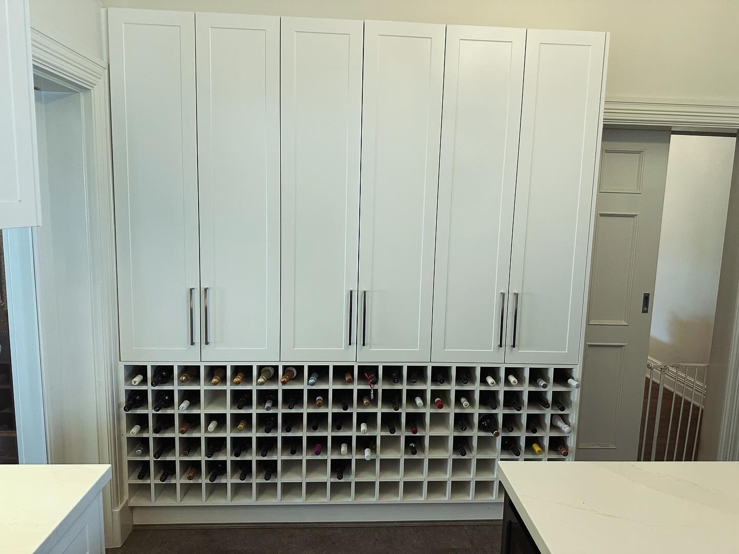 Floor-to-ceiling built-in wine storage cabinet with dozens of timber bottle racks