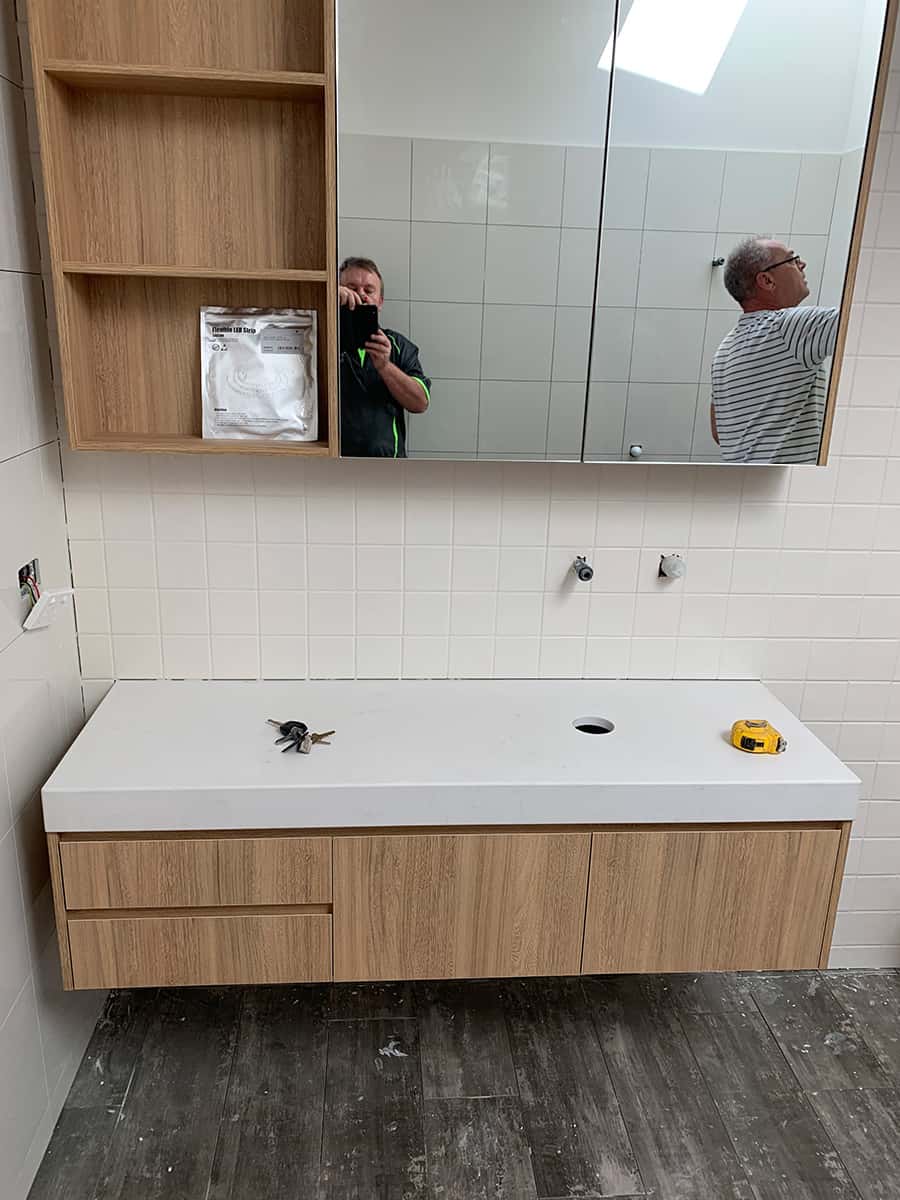 Oak floating bathroom vanity with a stone benchtop and matching mirror cabinet